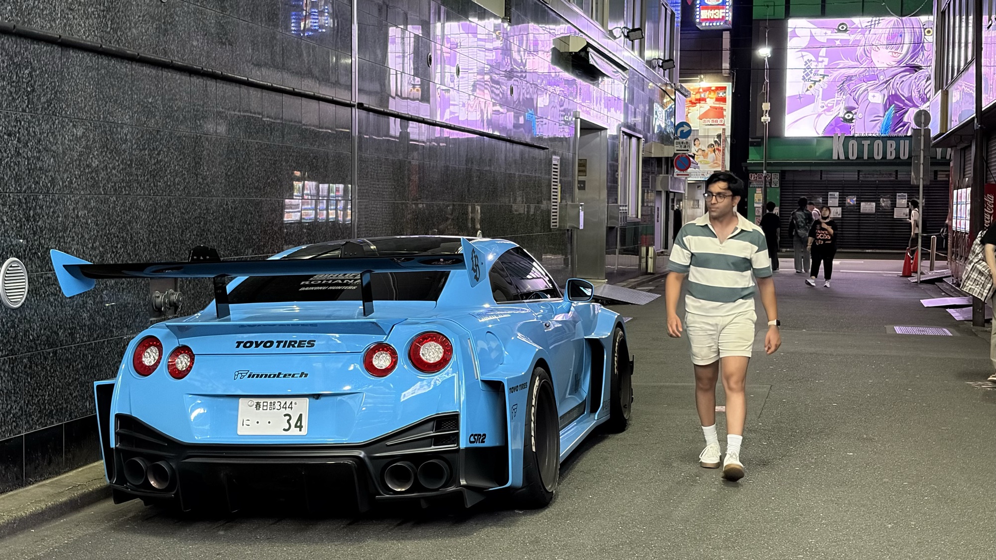 Kunal walking past a car in Tokyo